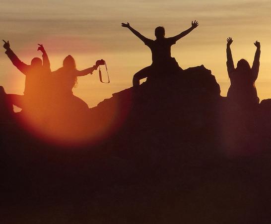 Students watch the sunset on top of a cliff during a j项 study tour.